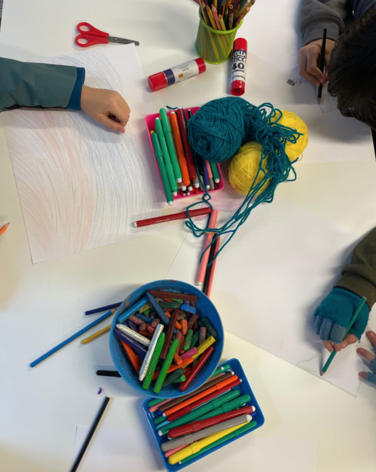 Participantes dibujando con ceras, rotuladores y lanas durante una actividad de arteterapia