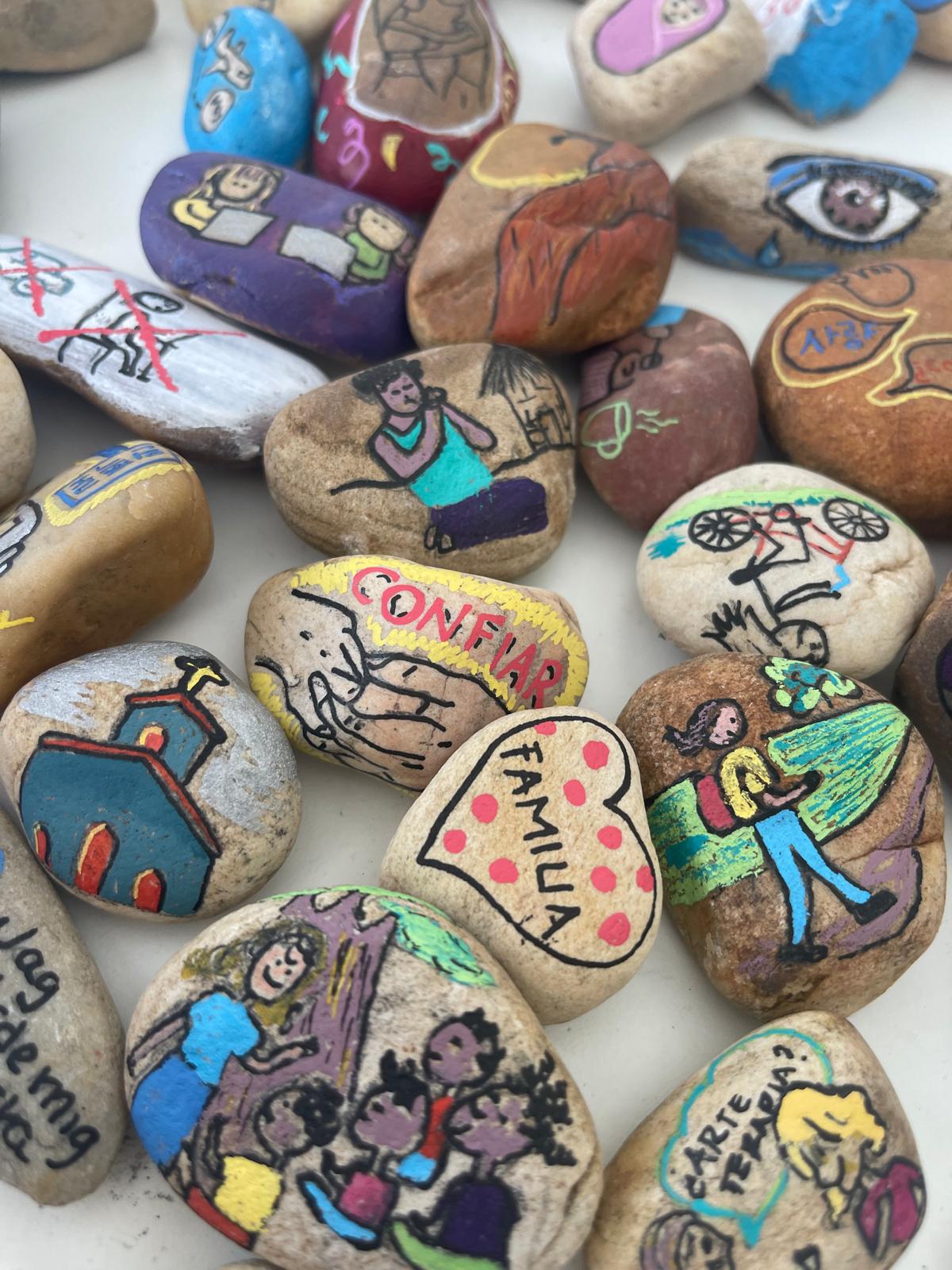Piedras pintadas con escenas y palabras como confiar y familia